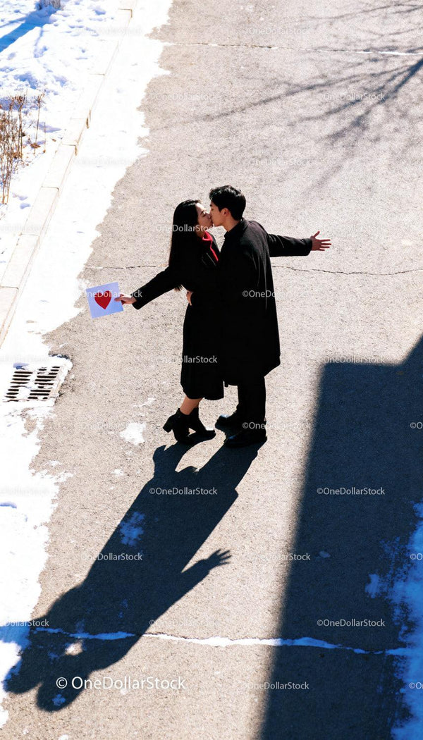 Couple sharing a kiss with love letter on snowy street