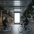 Urban commuters cycling past illuminated city billboard