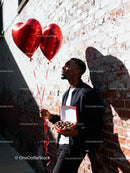 Man Holding Heart Balloons and Valentine Chocolates
