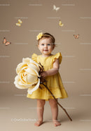 Toddler girl in yellow dress holding giant flower