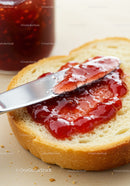 Spreading fresh strawberry jam on soft white bread