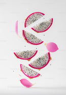 Slices of dragon fruit falling with pink flower petals