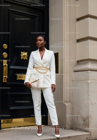 Elegant woman in white suit with gold accessories outdoors
