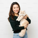 Young woman holding fluffy cream cat with gentle smile