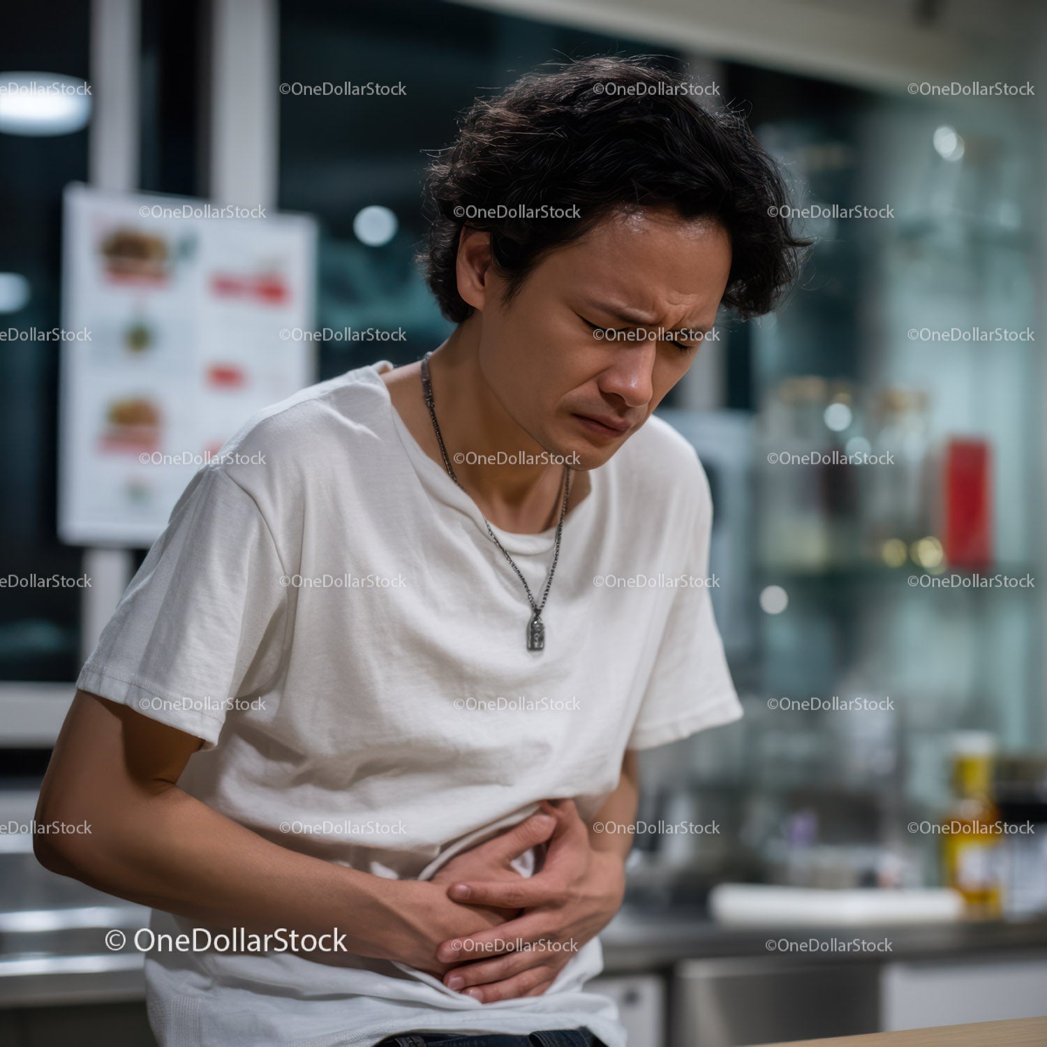 Young Man Experiencing Stomach Pain in Modern Indoor Setting