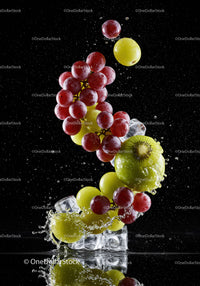 Fresh red and green grapes splashing with ice cubes