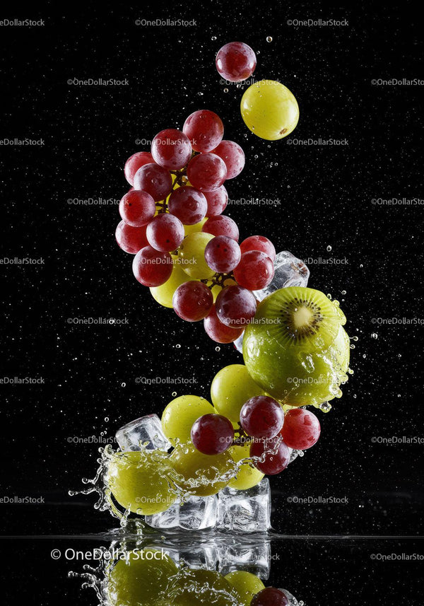 Fresh red and green grapes splashing with ice cubes