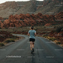 Woman Running Alone on Desert Road Surrounded by Rocks