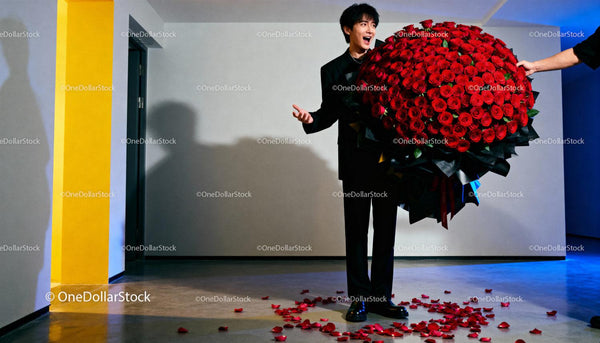 Excited young man holding gigantic bouquet of red roses