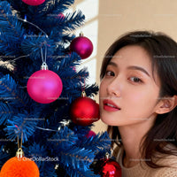 Young woman decorating vibrant blue Christmas tree