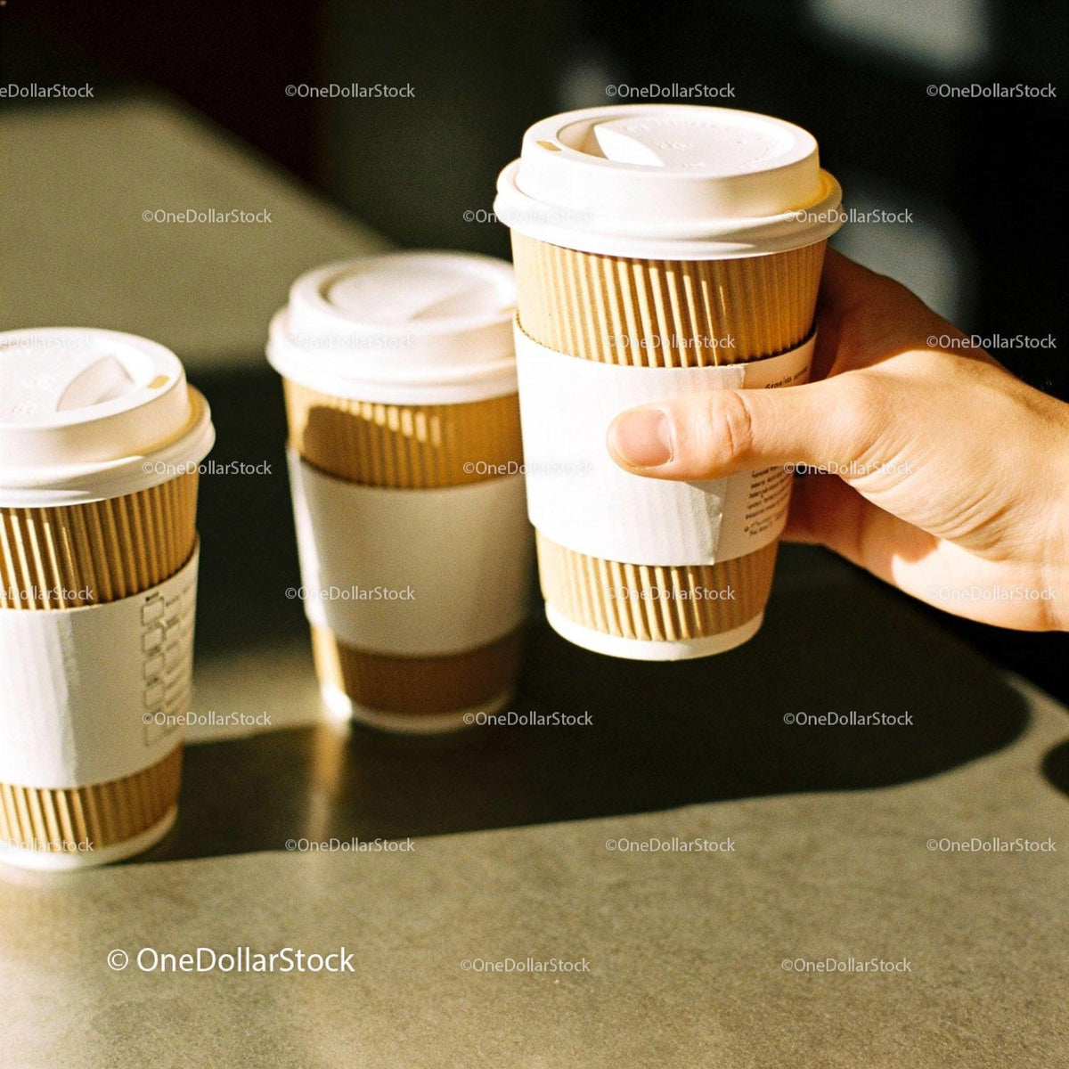 Hand Holding Takeaway Coffee Cup with Two Others Nearby