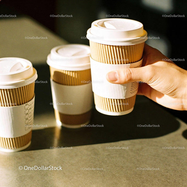 Hand Holding Takeaway Coffee Cup with Two Others Nearby