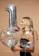 Smiling woman celebrating first birthday with balloons