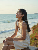 Elegant Woman in White Dress Sitting by Relaxing Seaside Landscape