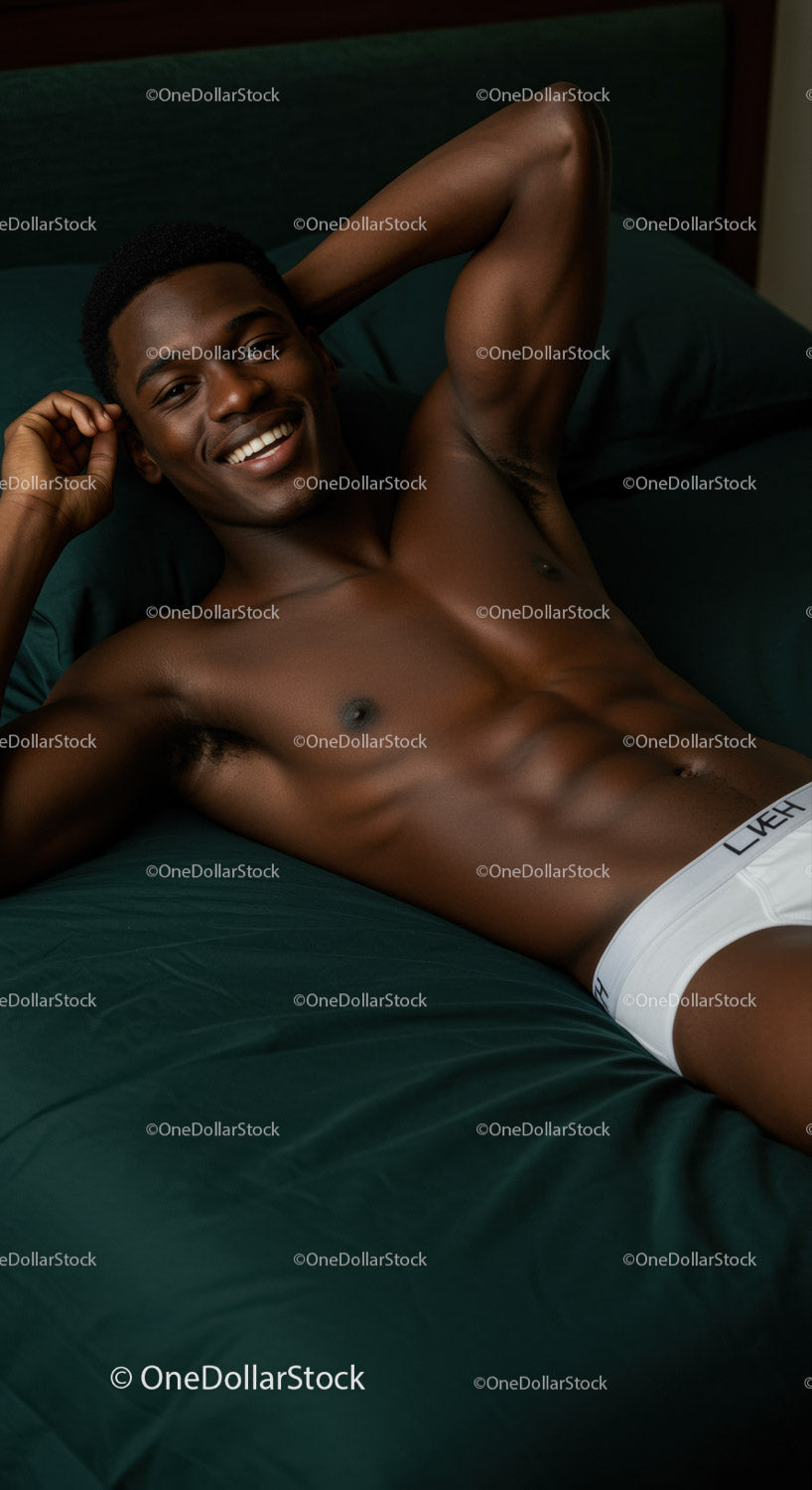 Smiling young man relaxing on dark green bed linen