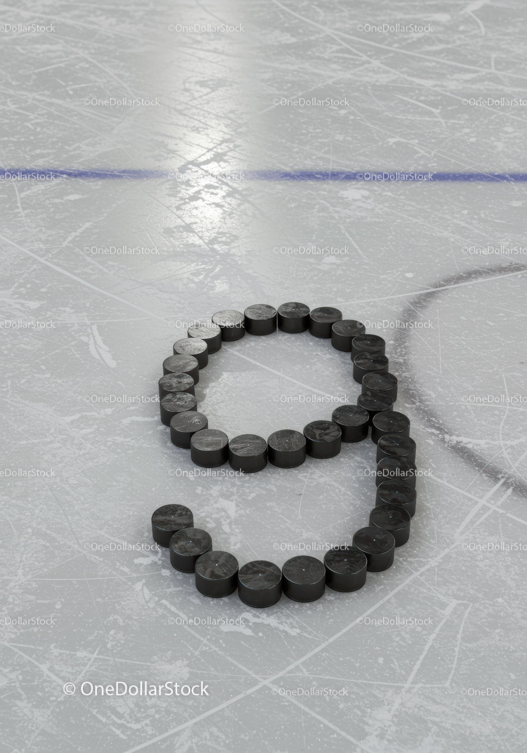 Hockey pucks arranged in number nine on ice rink surface