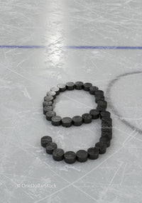 Hockey pucks arranged in number nine on ice rink surface