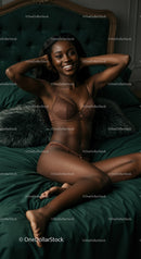 Smiling woman relaxing on dark green bed in lingerie