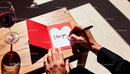 Man writing romantic message in Valentines card at table