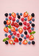 Fresh assorted berries scattered on pastel pink background