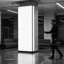 Blurred man walking past illuminated pillar in modern lobby