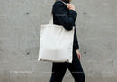 Person carrying blank canvas tote bag on shoulder