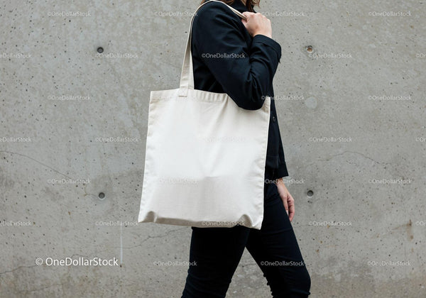 Person carrying blank canvas tote bag on shoulder JPG Mockup Image