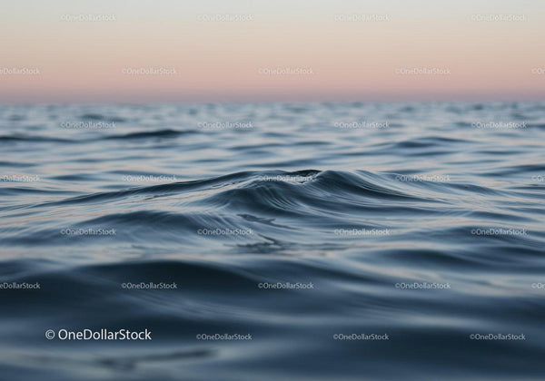 Spokojne fale oceanu pod zachodzącym słońcem nad spokojnym morzem