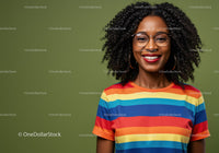 Smiling woman in rainbow striped shirt with curly hair and glasses