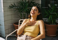Smiling Young Woman Relaxing Outdoors with Sunshine and Plants