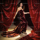 Elegant woman in velvet gown stepping through red curtains