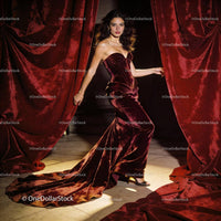 Elegant woman in velvet gown stepping through red curtains