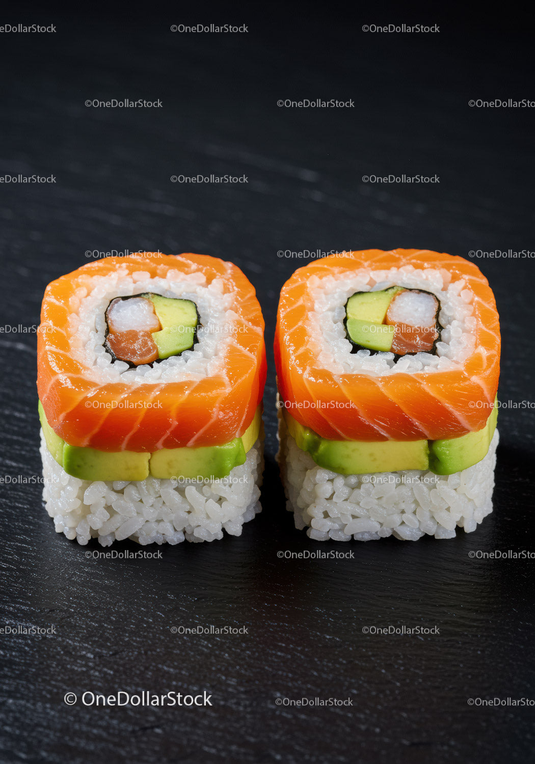 Two pieces of fresh salmon sushi with avocado slices