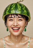 Joyful woman wearing watermelon helmet with water drops