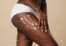 Close-up of a woman's thigh with hand applying skincare cream for body wellness