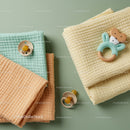 Soft baby blankets with pacifiers and toy on green background
