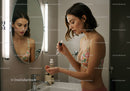 Young Woman Applying Skincare Using Dropper in Bathroom Mirror