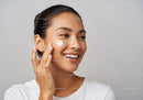 Smiling Woman Applying Skincare Cream For Healthy Glowing Skin