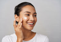 Smiling Woman Applying Skincare Cream For Healthy Glowing Skin
