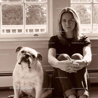 Calm woman sitting with her English Bulldog by window