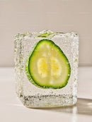 Fresh cucumber slice frozen inside crystal clear ice cube