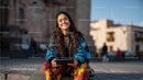 Young Woman Smiling while Sitting Outdoors on City Street