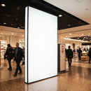 Blank illuminated advertising display in busy shopping mall