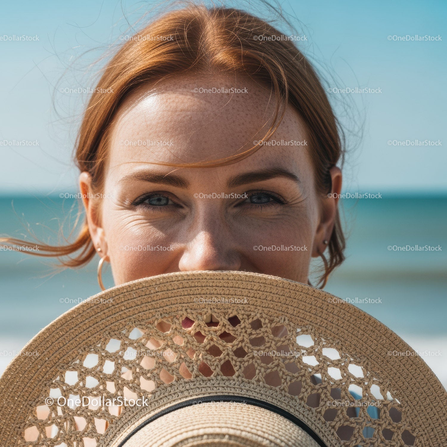 Smiling Red-Haired Woman Covering Face with Straw Hat at Beach