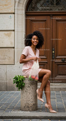 Smiling woman in pink dress holding fresh groceries outdoors