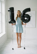 Young woman celebrating sixteenth birthday with balloons