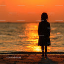 Silhouette of a Child at Sunset by the Ocean Shore