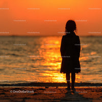 Silhouette of a Child at Sunset by the Ocean Shore