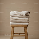 Stack of Soft Beige Textured Blankets on Wooden Stool