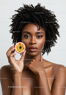 Elegant African American Woman with Curly Hair Holding Passion Fruit Slice